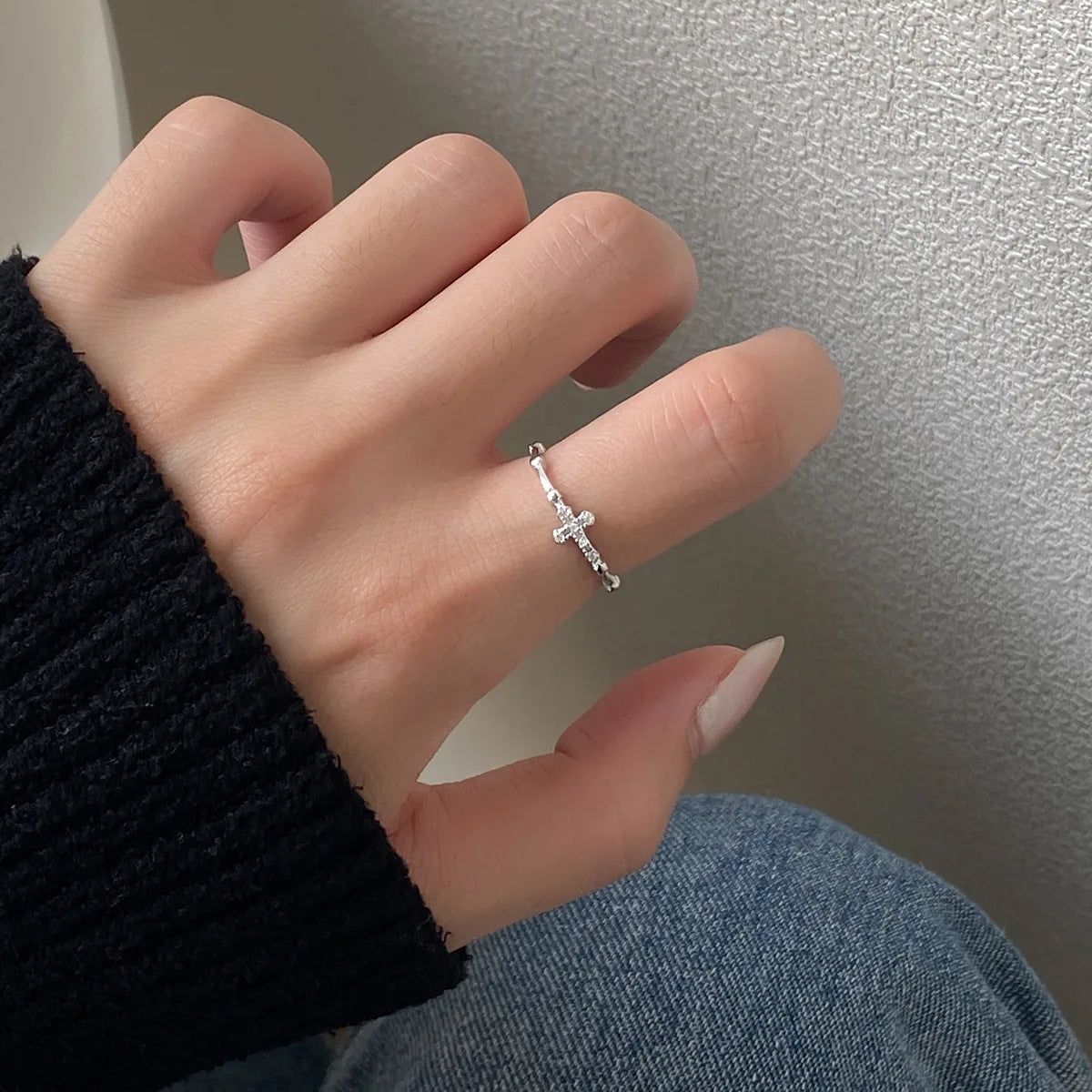 cross ring surrounded by small clear silver-colored diamonds